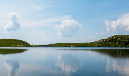 Two tourists silhouette walking on a lake in Austria Alps mountain