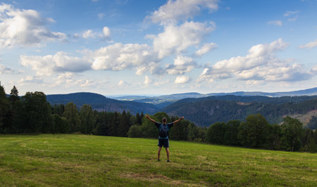Man with backpack and hands up standing on meadow.の写真素材