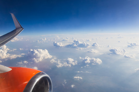Aerial cumulus cloud from plane window with wing and engine. Travel backgroundの写真素材