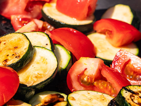 Fresh tomatoes and sliced zucchini sizzle on a hot grill, creating colorful, smoky vegetables. The scene highlights healthy summer cooking, vibrant ingredients, and delicious homemの写真素材
