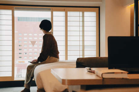 Female short hair female model looking out windowの写真素材