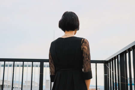 Short-haired female model looks out at the city from rooftop