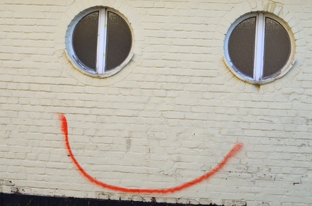 A smile in the spring face graffiti on a wall with little effort by a line between two windows a smile brought to the wall Despite Schmierereii it prepares a smileの写真素材
