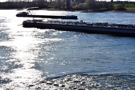 Two Barges at full speed, the evening sun reflected in the fairwayの写真素材