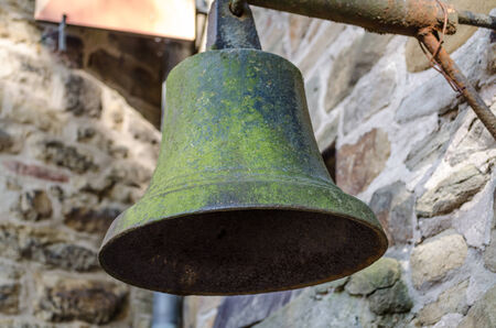 Old bell suspended on a metal bracketの写真素材