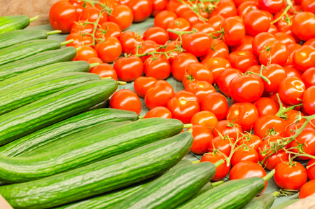 Various tomatoes and cucumbers for sale at a farmers marketの写真素材