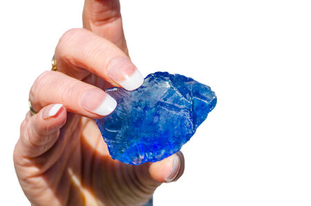 Quartz stone, glass stone pieces in blue held by a hand against white backgroundの写真素材