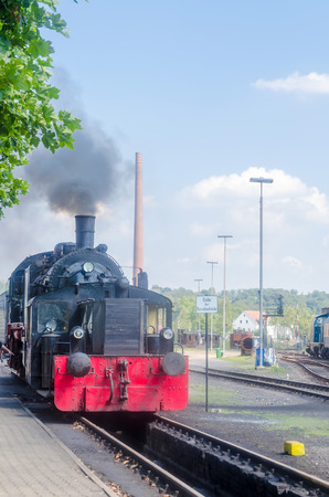 Departure and rear view of a steam locomotive under full steam at the exit from the station.のeditorial素材