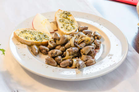 Grilled chicken hearts on a white plate with garlic bread.の写真素材