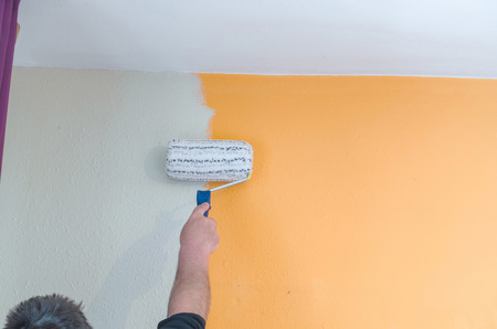 Hand with paint roller renovating. Painting a wall with white paintの写真素材