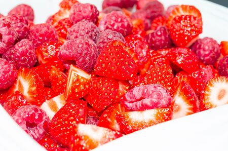 Fresh strawberries and raspberries in white bowl.の写真素材