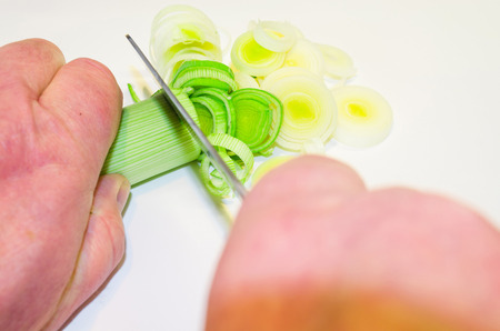 Hand of the cook, while cutting vegetables on a wooden board.の写真素材