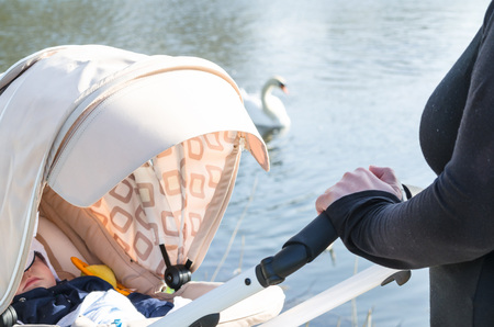 Sleeping little boy on a walk is in a stroller with a white cap.の写真素材