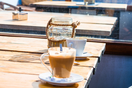 A cup of milk with coffee on the table of a beach bar. Background slightly blurred.の写真素材