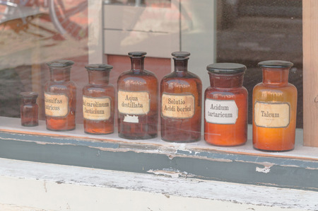 Historic old pharmacy bottles with label in a shop window.の写真素材