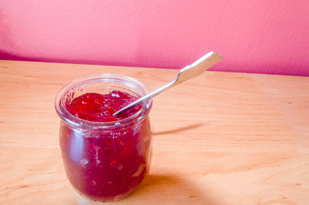 Homemade red jam in a small jar with spoon