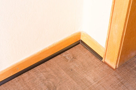 Installation of a wood baseboard at the bottom of a wall after installing flooring.の写真素材