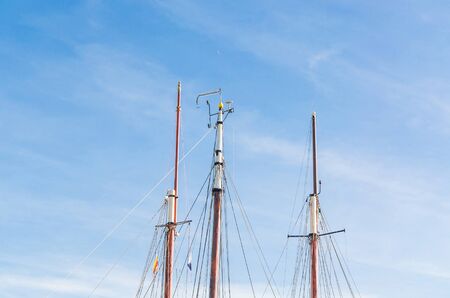 Various ship masts in a marina in Netherlands, against a bright blue sky.の写真素材