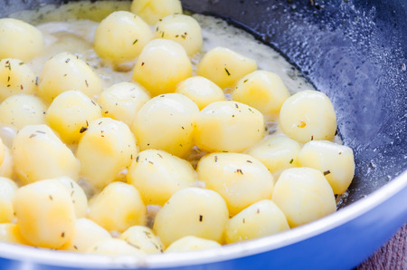 Baked potatoes in frying pan seasoned with rosemary.の写真素材