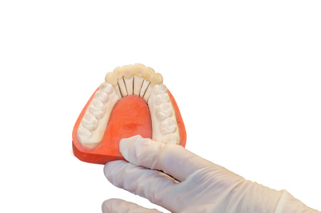 Dentures, prosthesis and oral hygiene. Hands with gloves while working on a prosthesis, false teeth,...