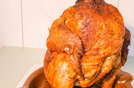 Close up of a brown roasted grilled chicken on a grill poultry holder.の写真素材