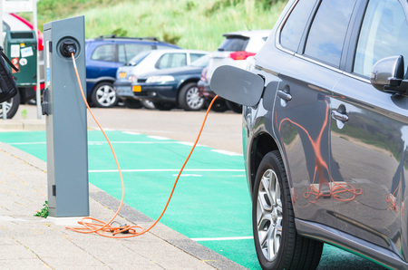 Den Haag, Scheveningen, The Netherlands - June 17, 2015: electric car at a charging station on the beach parking in Scheveningen Holland.Seperate parking with Charging Station for Electric Vehicles. Vehicles Can Be Connected by Cable to the station for reのeditorial素材