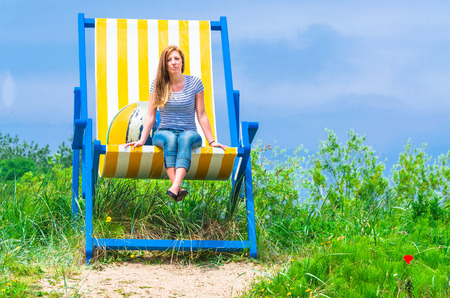 Gigantic deckchair with young women in front of a blue sky.の写真素材