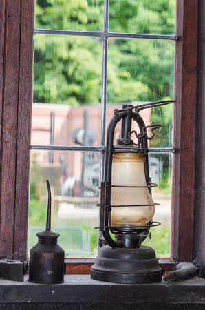 Old kerosene lamp on a window sill in the background a lattice window.の写真素材