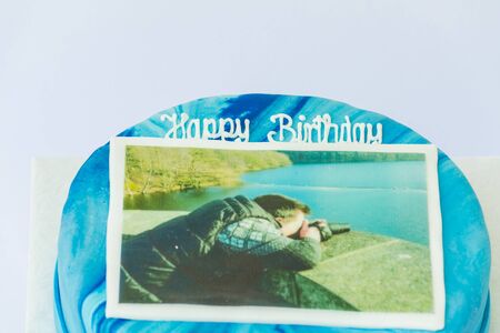 Birthday cake with dark and light blue pattern. In the middle of an image. Man with camera.の写真素材