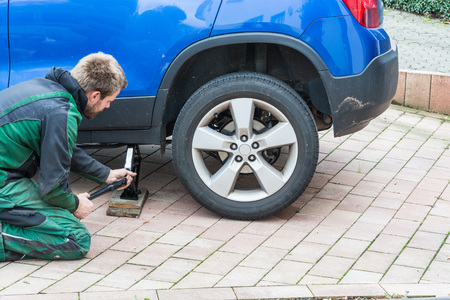Young man  exchanging the car tires. From summer tires on winter tires on his car.の写真素材
