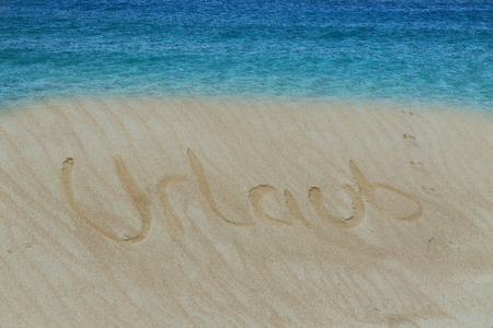 Golden sand with a drawn in the sand heart.Turquoise water and golden sand with a subscribed in the sand word in German holiday.の写真素材