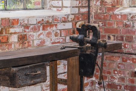 Old black bench vice installed on a workbench.