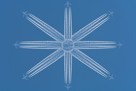 Eight aircraft at high altitude flying in star-shaped formation. Contrails against a dark blue sky.