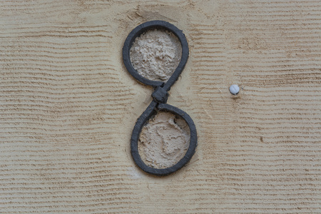 Rusty antique wall anchor in an old yellow painted and plastered stone wall.の写真素材