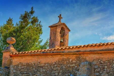 Church tower with bell in Spanish style against a blue sky.の写真素材
