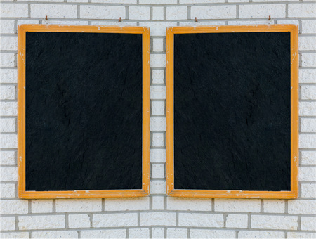 Two empty large slate boards with wooden frame on a stone wall.の写真素材