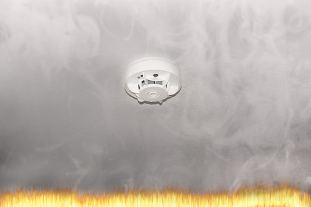 Smoke detector on the ceiling with red warning light sensor and smoke.の写真素材