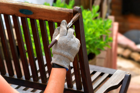 Painting and applying protective varnish on a wooden garden chairの写真素材