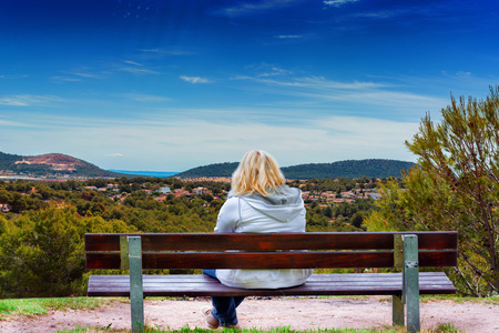 Woman sitting on a bench with panoramic view over Paguera towards bay of Palma, Mallorca in Spain.の写真素材