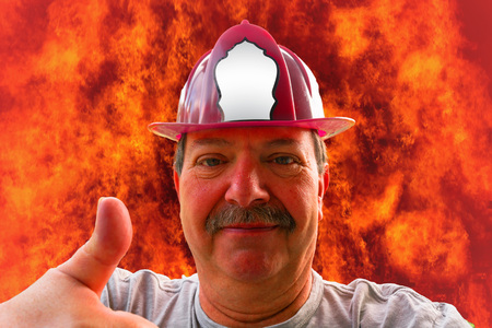 Portrait of a firefighter with helmet, fire in the background a flame sea.