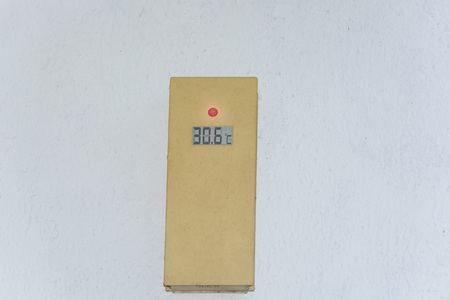 Thermometer on a white exterior wall shows 30 degrees. Concept hot summer day.の写真素材