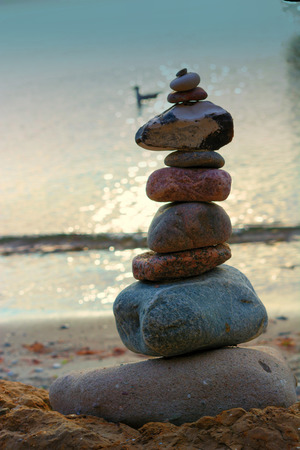 Stones stacked on top of each other on the beach with sea view in the background