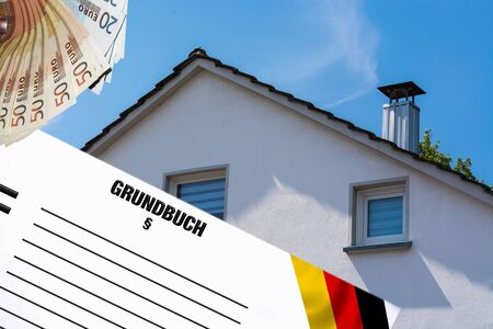 Gable side of a multi-family house of the 60s after the modernization against the blue sky. In the foreground white note with inscription in german land register.の写真素材