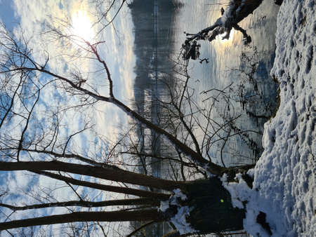 Calm pond on cold winter day. Peaceful lake water and snowy coast on cold gray day in winter countrysideの写真素材