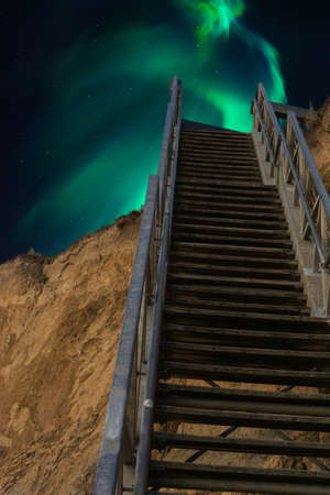 Stairs from the direction of the beach in the background of the night starry sky, with northern lights, cosmic spaceの写真素材