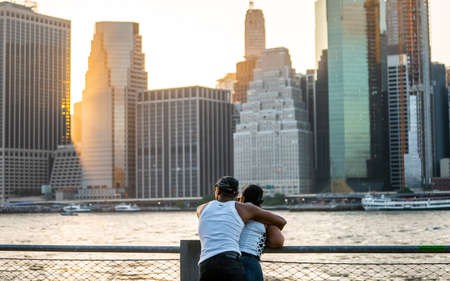Romantic couple looking to Manhattan skyline from Brooklyn riverside during sunset , New york city , United States of America - September 3 , 2018のeditorial素材