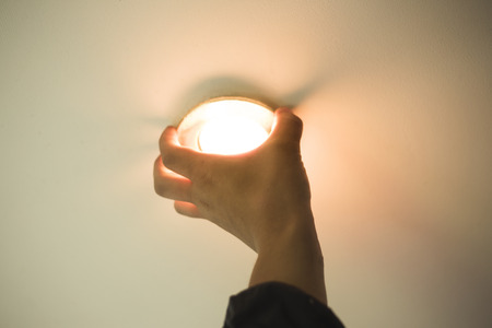 installation of point light, hand inserts the lamp into the ceiling close-up