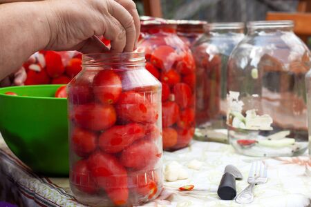 grandmother canning  sorts seasoning jars and bay leaves for pickled tomatoes, preservation canning process close-upの写真素材