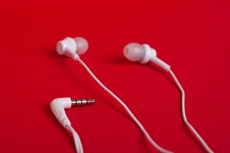 Concept: white headphones (earphones) and mini jack on a red background closeupの写真素材
