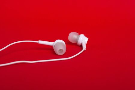 Concept: white headphones (earphones) on a red backgroundの写真素材